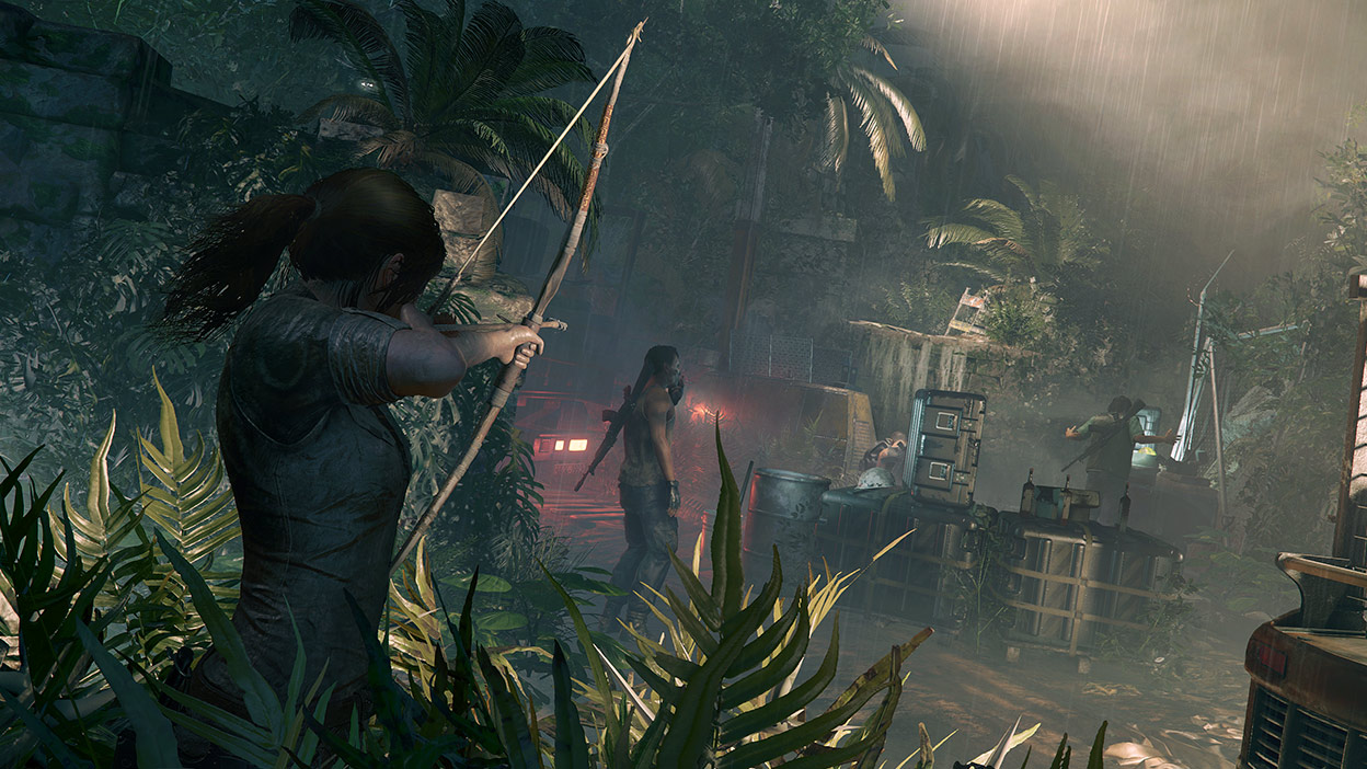 Lara Croft napina łuk wycelowany w mężczyznę stojącego w małym obozowisku