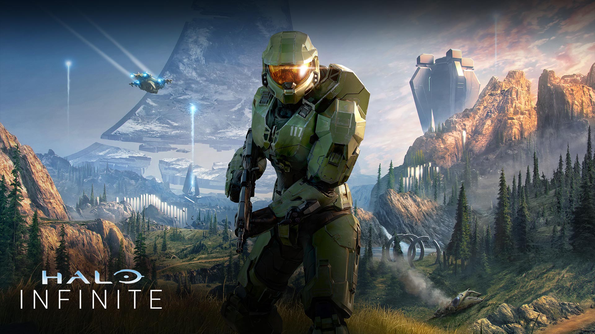 Master Chief faces forward in a lush valley with a broken Halo ring behind him