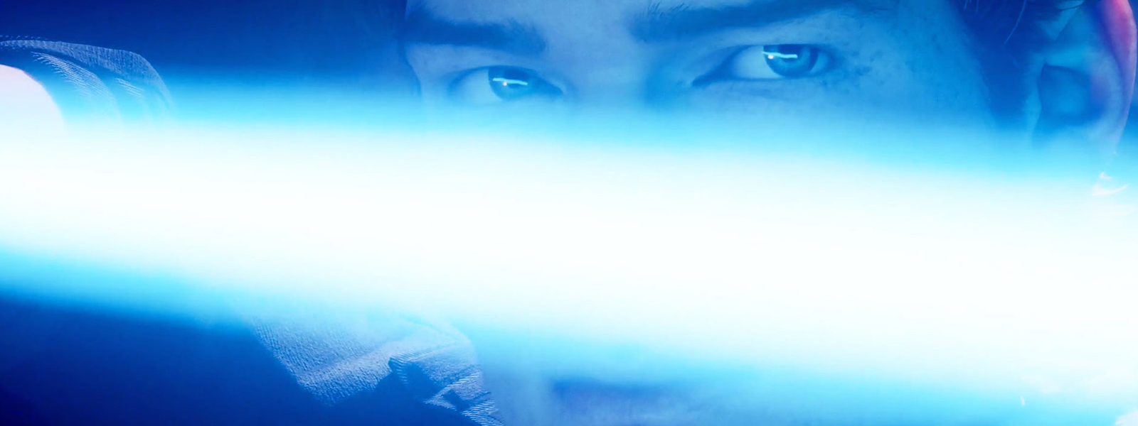 Close-up de Cal Kestis segurando um sabre de luz na frente do rosto.