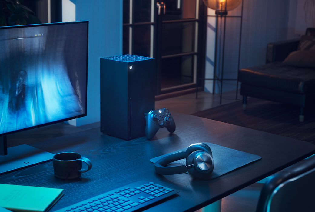 Sluchátka Bang and Olufsen položená vedle Xboxu Series X a počítače