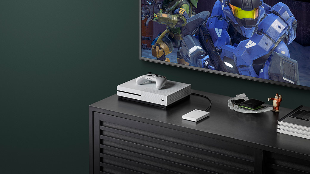 Xbox One S и геймпад Xbox рядом с телевизором, на экране которого показана Halo 5: Guardians