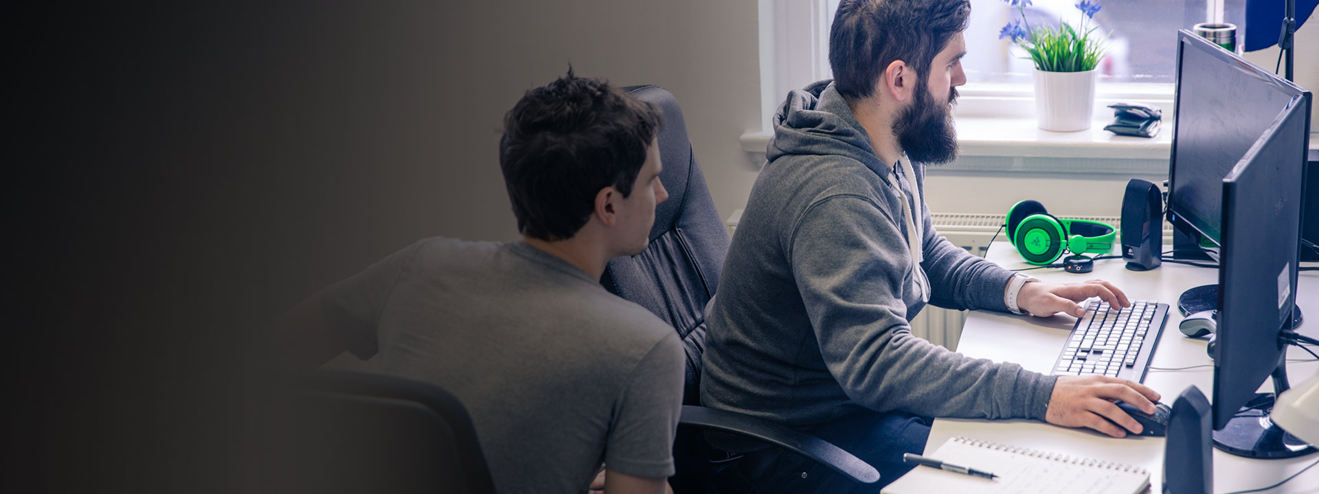Mies ja nainen istuvat työpöytiensä ääressä kehittämässä Xbox-peliä ID at Xbox -ohjelman puitteissa