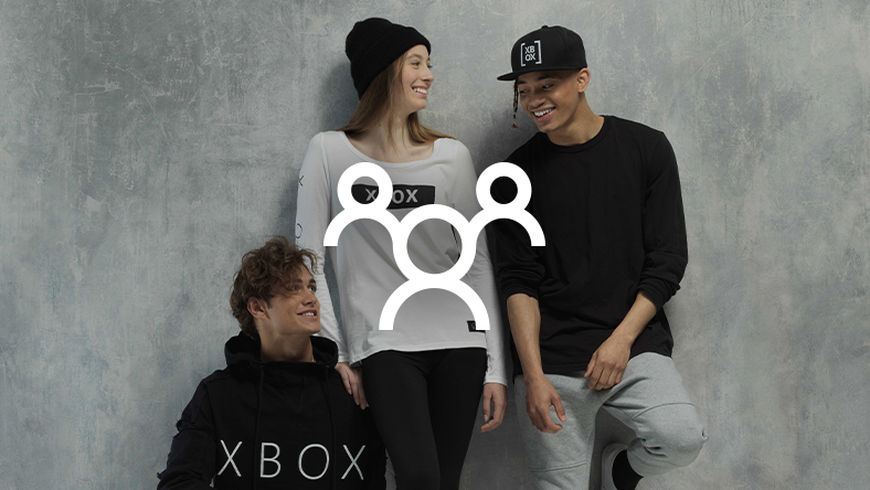 กลุ่มคนที่ใบหน้ายิ้มแย้มซึ่งสวมอุปกรณ์แท้ของ Xbox มีรูปร่างคนสามคนวางซ้อนอยู่