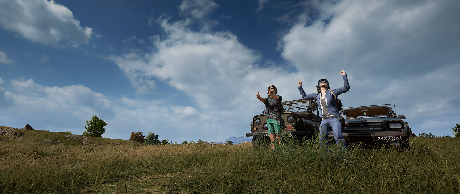 Two players point finger-guns in front of old cars in a field. 